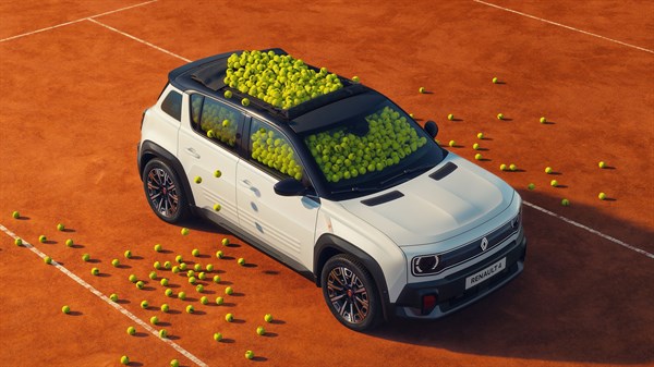 Beli Renault 4 Roland Garros posebne izdaje, fotografiran od zgoraj na rdeči peščeni teniški podlagi s teniškimi žogicami na strehi in okoli vozila.