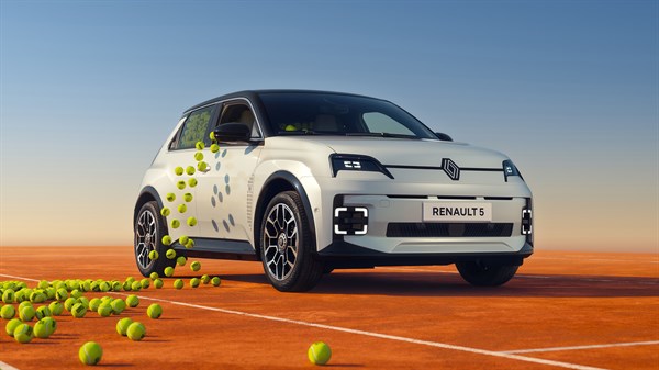 Beli Renault 5 Roland Garros posebne izdaje na rdeči peščeni teniški podlagi z motivom teniških žogic na karoseriji in okoli vozila.