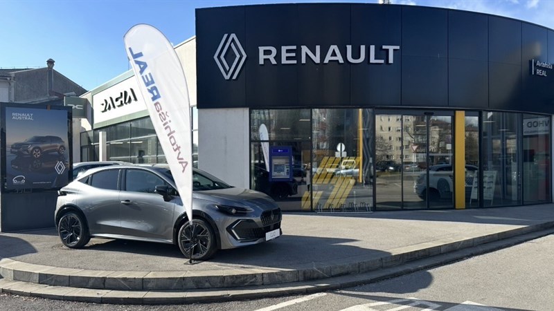 Stavba Avtohiša Real s steklenimi stenami, avtomobili so vidni v notranjosti.