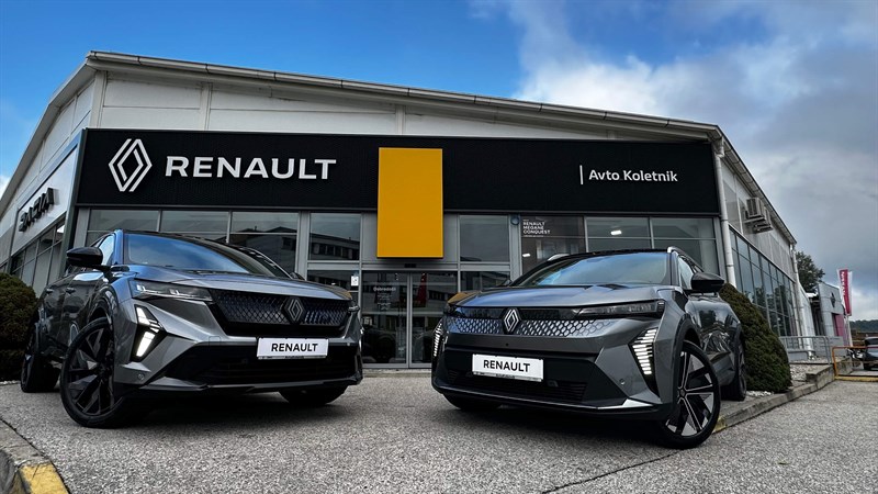 Dve sivi Renault vozili parkirani pred salonoma Avto Koletnik, nad vhodom velik napis Renault.