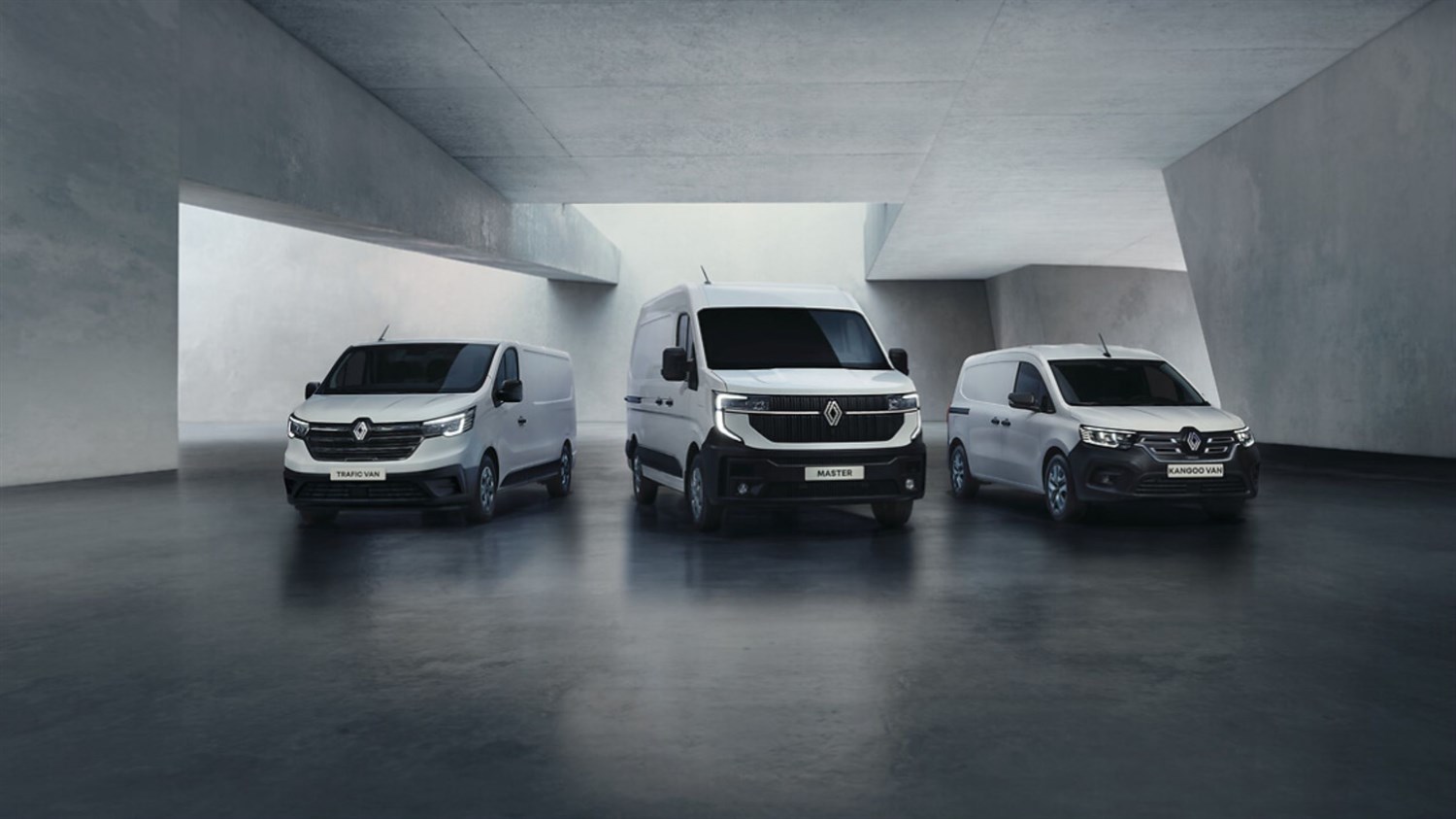 Na sliki so trije beli dostavni kombiji znamke Renault, postavljeni v sodoben, minimalističen betonski prostor.