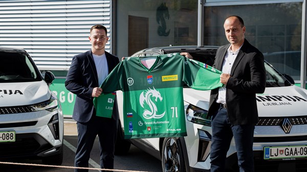 Predstavnika HK SŽ Olimpija in podjetja Renault Slovenija stojita pred električnimi vozili Renault Symbioz ter držita zelen dres z logotipom kluba.
