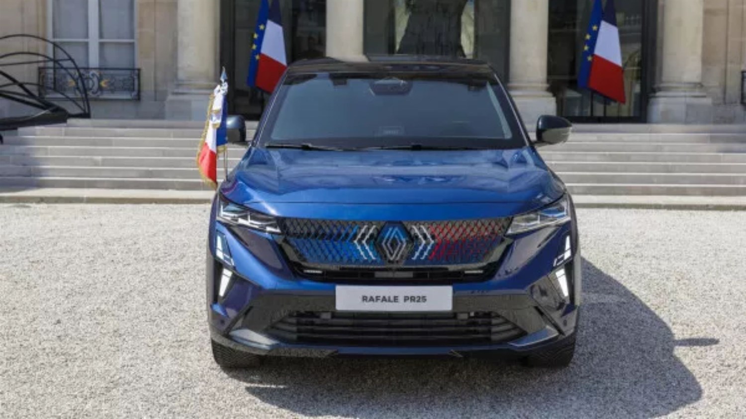 Temno moder SUV Renault Rafale parkiran na prodnatem dvorišču pred neoklasično stavbo s stebri in francoskimi zastavami.