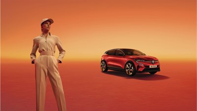 Ženska v svetlih elegantnih oblačilih stoji pred rdečim Megane E-Tech vozilom.