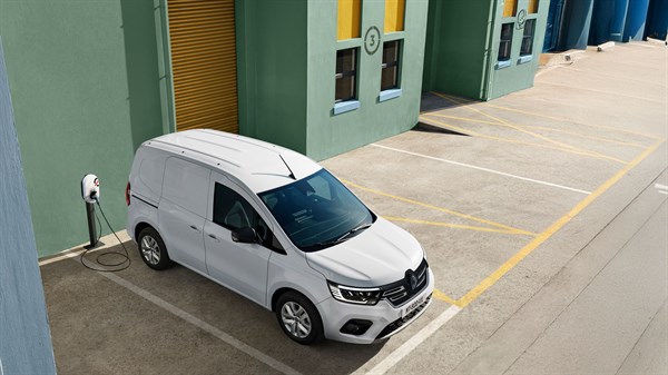 Bel Renault Kangoo, parkiran ob polnilnici pred modro stavbo.