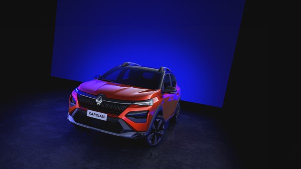 Oranžen Renault Kardian, osvetljen s sprednje strani, na črnem ozadju z modro svetlobo v ozadju.