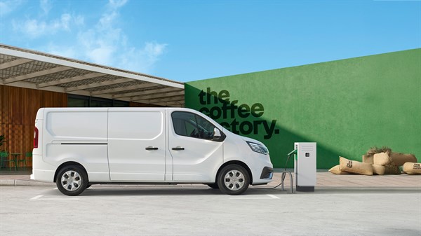 Bel Renault Trafic Van, parkiran ob polnilnici pred zeleno steno z napisom "the coffee factory".