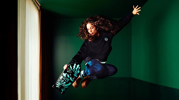 Skateboardistka v zraku z desko z grafiko Renault v sodobnem prostoru.