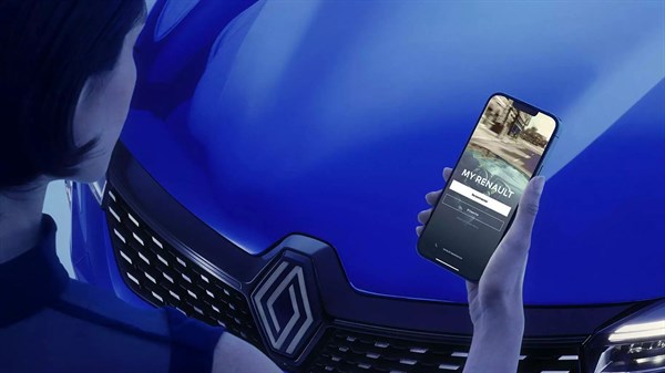 Oseba drži pametni telefon s prikazom aplikacije My Renault pred sprednjim delom vozila Renault.