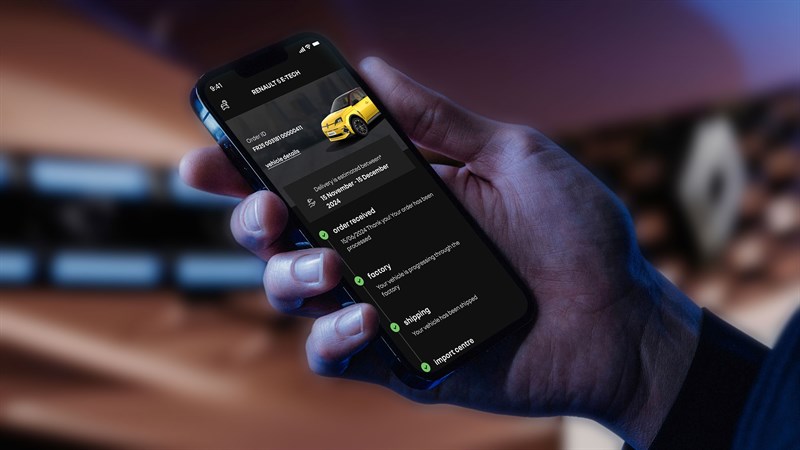 Roka drži pametni telefon z aplikacijo za sledenje naročilu Renault 5 E-Tech, prikazani so statusi proizvodnje in dostave.