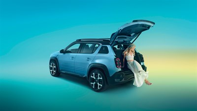 Ženska sedi v odprtem prtljažniku svetlomodrega Renault 4 na barvnem ozadju.