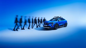 Renault Rafale E-Tech v živo modri barvi z nosilcem za prtljago na strehi, parkiran v futurističnem prostoru z zamegljenimi silhuetami ljudi v gibanju v ozadju.