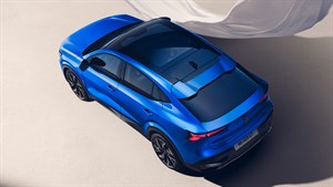 Renault Rafale je prikazan od zgoraj na svetli podlagi, z odprto panoramsko streho in elegantnimi linijami, v ozadju plapola bel tančica.