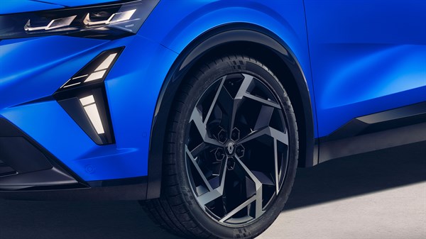 Povečan pogled na sprednje levo kolo modrega vozila Renault Rafale, ki poudarja dinamično oblikovana črna platišča z grafičnimi srebrnimi elementi ter izrazito LED osvetlitev v odbijaču in ostre linije blatnika.