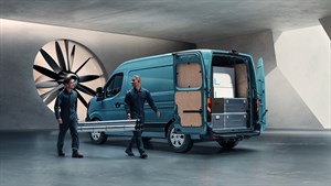 Na sliki je moder dostavni kombi Renault z odprtimi zadnjimi vrati. V notranjosti je prostor za tovor, deloma obložen z lesom in opremljen s predali za shranjevanje.