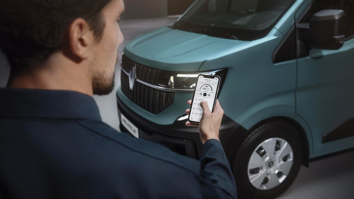 Moški upravlja aplikacijo na pametnem telefonu za povezljivost z dostavnim vozilom Renault Master, prikazan je prednji del električnega vozila.