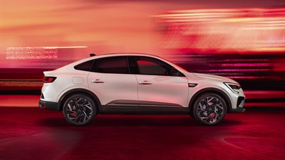 Beli Renault Megane Conquest med vožnjo, stranski pogled z dinamičnim rdečim ozadjem.