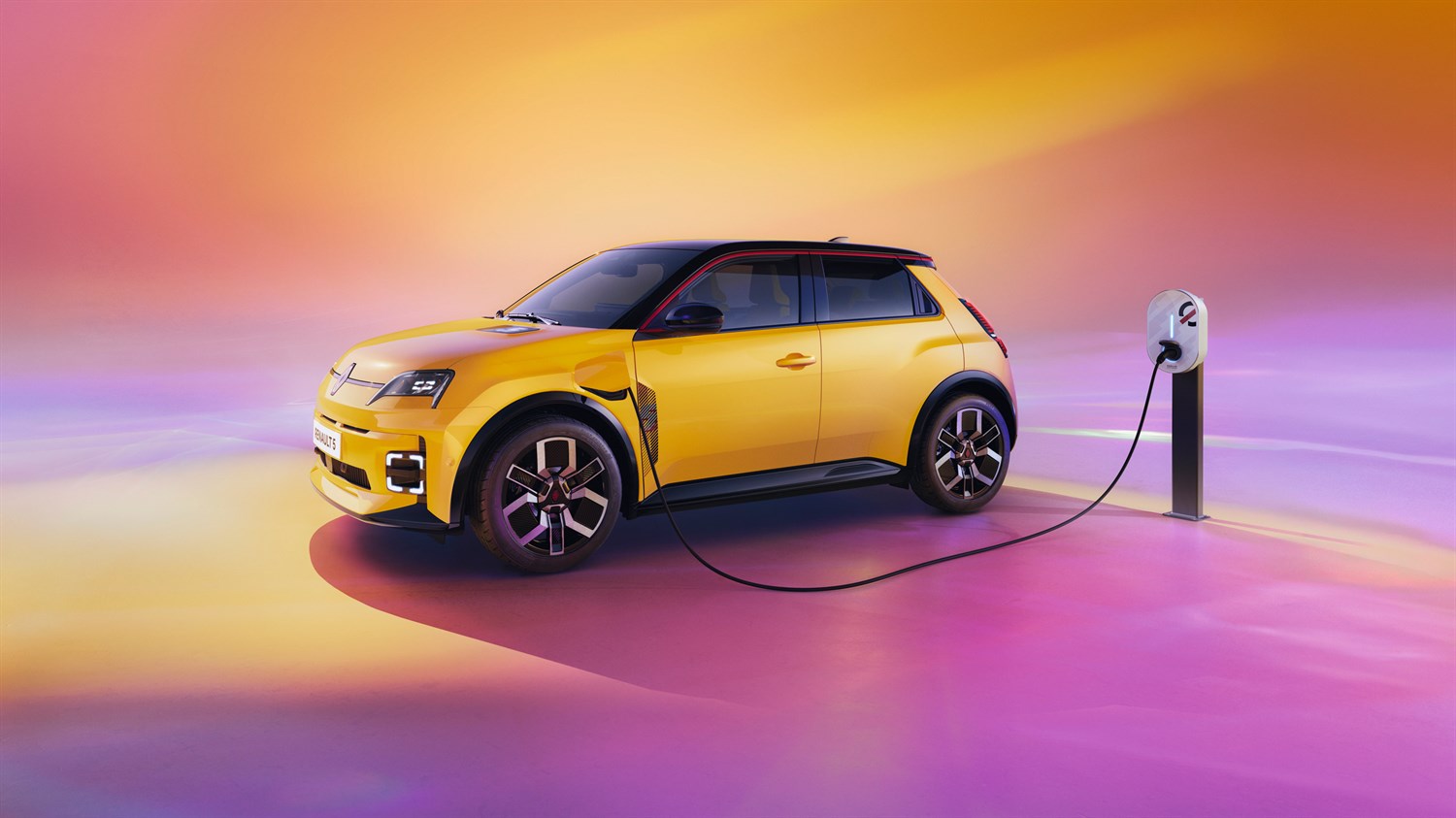 Renault 5 v studijskem okolju priklopljen na stoječo polnilnico. 