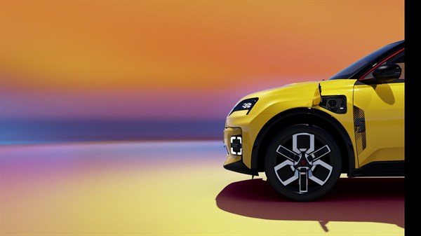 Sprednji del rumenega Renault 5 E-Tech s priključkom za polnjenje in platišči, na barvitem ozadju.