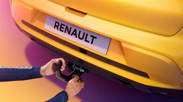 Oseba odstranjuje snemljivo vlečno kljuko z zadnjega dela rumenega Renault 5.
