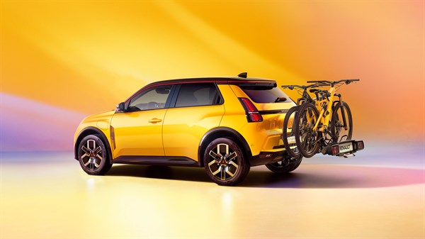 Renault 5 E-Tech rumene barve s pritrjenim nosilcem za kolesa na zadnjem delu.