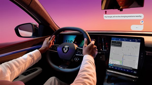 Voznik uporablja volan in osrednji zaslon z navigacijo, v vzvratnem ogledalu je prikazano glasovno sporočilo Google Assistant