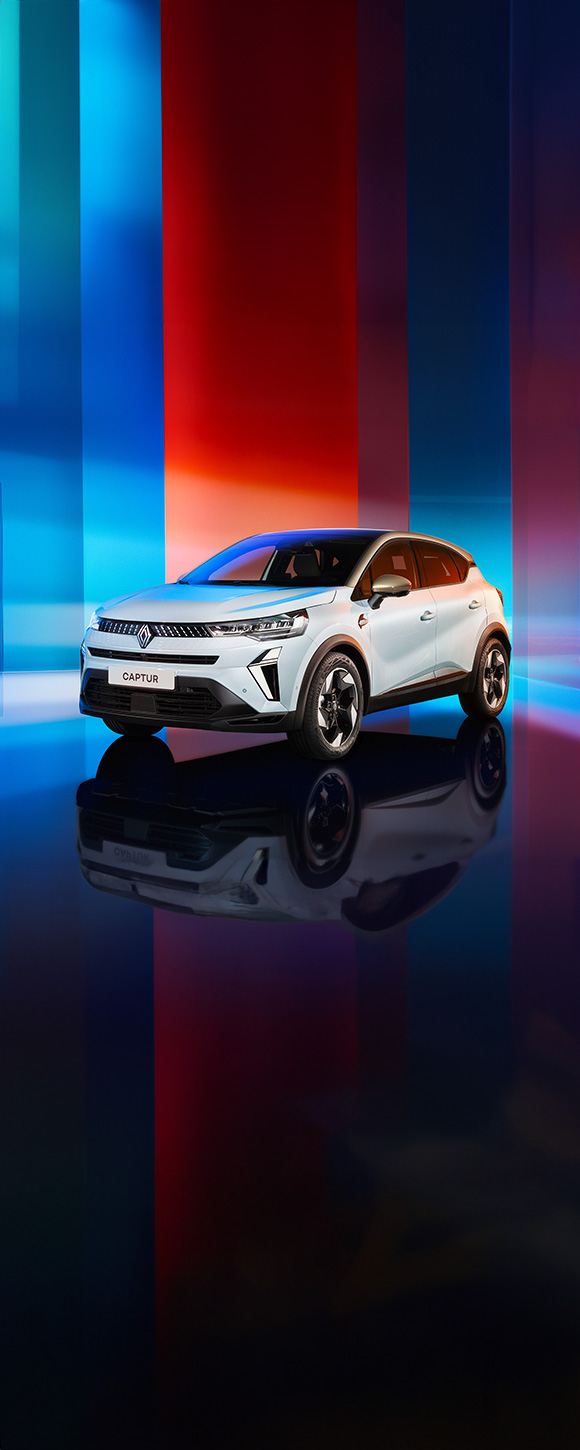 Renault Captur osvetljen v studijskem okolju z večbarvnim ozadjem, viden s sprednje leve strani.