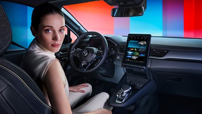Ženska na voznikovem sedežu vozila Renault se ozira nazaj, v ozadju osvetljena armaturna plošča.