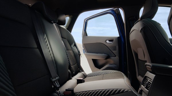 Pogled na zadnje sedeže vozila Renault Captur z odprtimi vrati, ki razkrivajo prostorno in udobno notranjost z modernimi sedeži in kakovostnimi materiali.
