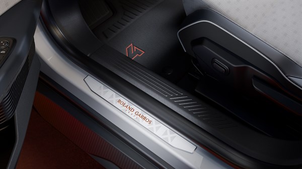 Detajl pragа vratа z napisom »Roland Garros« in oranžnim logotipom Renault v notranjosti posebne izdaje.