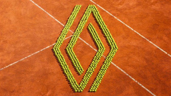 Logotip Renault sestavljen iz teniških žogic na rdeči peščeni teniški podlagi.