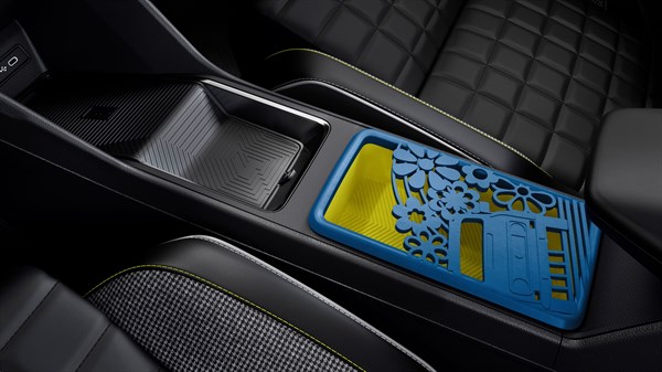 Notranjost Renault 4 E-Tech Electric: sredinska konzola s predalom, modrim snemljivim vložkom z vzorcem izrezljanih oblik in rumenim dnom.