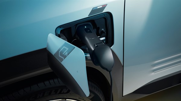 Odprt pokrov polnilnega vtiča na levi sprednji strani Renault 4 E-Tech Electric z vstavljenim polnilnim kablom.
