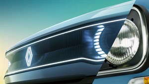 Detajlni pogled na sprednji del vozila, razdeljen na dve polovici – leva prikazuje sodobno LED osvetlitev z osvetljenim logotipom Renault, desna pa klasični okrogli žaromet s kromiranim robom, kar nakazuje kontrast med moderno in retro obliko.