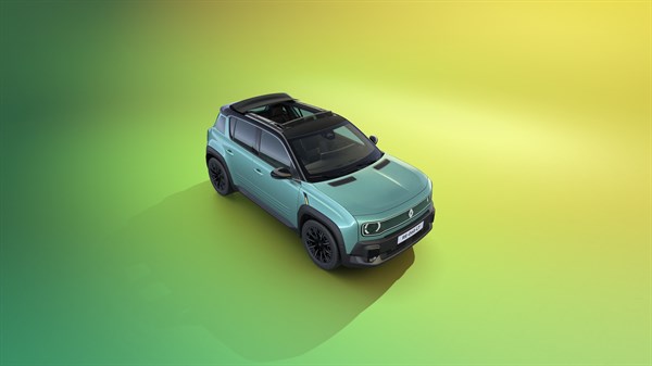 Vozilo Renault med vožnjo po mestni cesti ob sončnem zahodu.