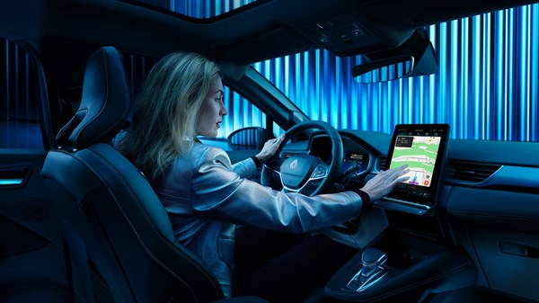 Ženska sedi za volanom Renault Symbioz in upravlja osrednji zaslon na dotik.