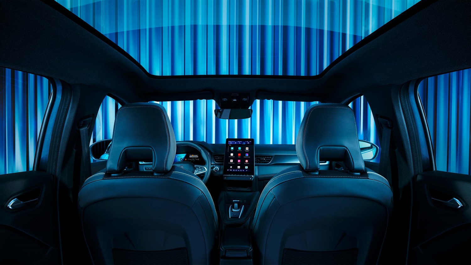 Pogled iz zadnjih sedežev vozila Renault Symbioz proti armaturni plošči, z odprtim panoramskim steklenim strešnim oknom in osrednjim digitalnim zaslonom na dotik.