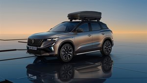 Renault Austral parkiran ob sončnem zahodu z nameščenim strešnim kovčkom za dodatno prtljago.