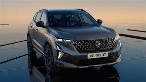 Na sliki je temno siv Renault Austral, predstavljen s sprednje strani na odsevni površini ob sončnem zahodu. 