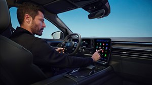 Moški upravlja velik osrednji zaslon na dotik v sodobni notranjosti vozila Renault Austral s panoramskim pogledom.