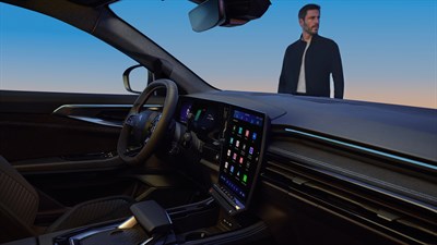 Moški stoji ob modrem Renault Austral, parkiranem na odsevni površini ob sončnem zahodu.