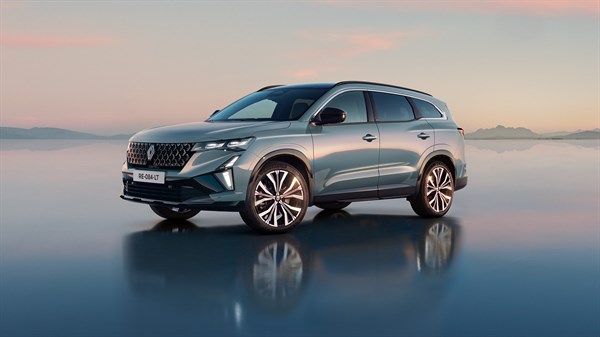 Renault Espace v svetlo modro-srebrni barvi, pogled od spredaj-levo ob sončnem zahodu, parkiran na odsevni površini.