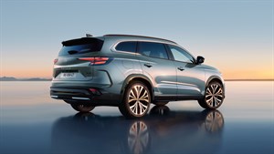 Vozilo Espace slikano z boka parkirano na stekleni površini obdano s sončnim zahodom.