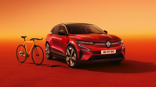 Rdeč Renault Megane E-Tech parkiran poleg rumenega kolesa, povezanega s kablom, na oranžno-rdečem ozadju.