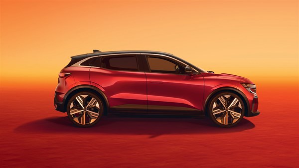 Renault Megane E-Tech Electric v profilu, rdeča barva karoserije s črno streho, postavljen na oranžno rdečem ozadju z osvetljenim nebom.