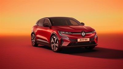 Renault Megane E-Tech Electric v sijoči rdeči barvi, parkiran v osvetljenem ambientu z oranžno ozadjem.