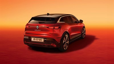 Zadnji pogled na Renault Megane E-Tech Electric v rdeči barvi s črno streho, osvetljen z oranžno-rdečo svetlobo v ozadju sončnega zahoda.