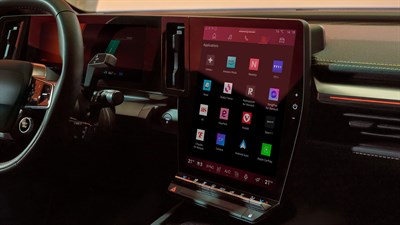 Osrednji zaslon na dotik v notranjosti vozila Renault Megane E-Tech Electric, prikazuje različne aplikacije, vključno z Netflix, Spotify in Waze, obdano z ambientalno osvetlitvijo in delno vidnim volanom.