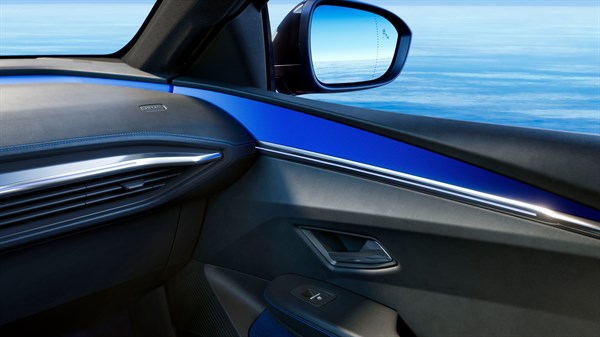 Pogled na notranjost sovoznikove strani vozila Renault Megane E-Tech z modrimi in kovinskimi okrasnimi elementi ter zunanjim ogledalom.