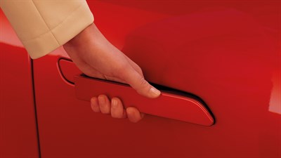 Roka osebe, ki sega po izvlečnem kljuku na vratih vozila Renault Megane E-Tech Electric v rdeči barvi.
